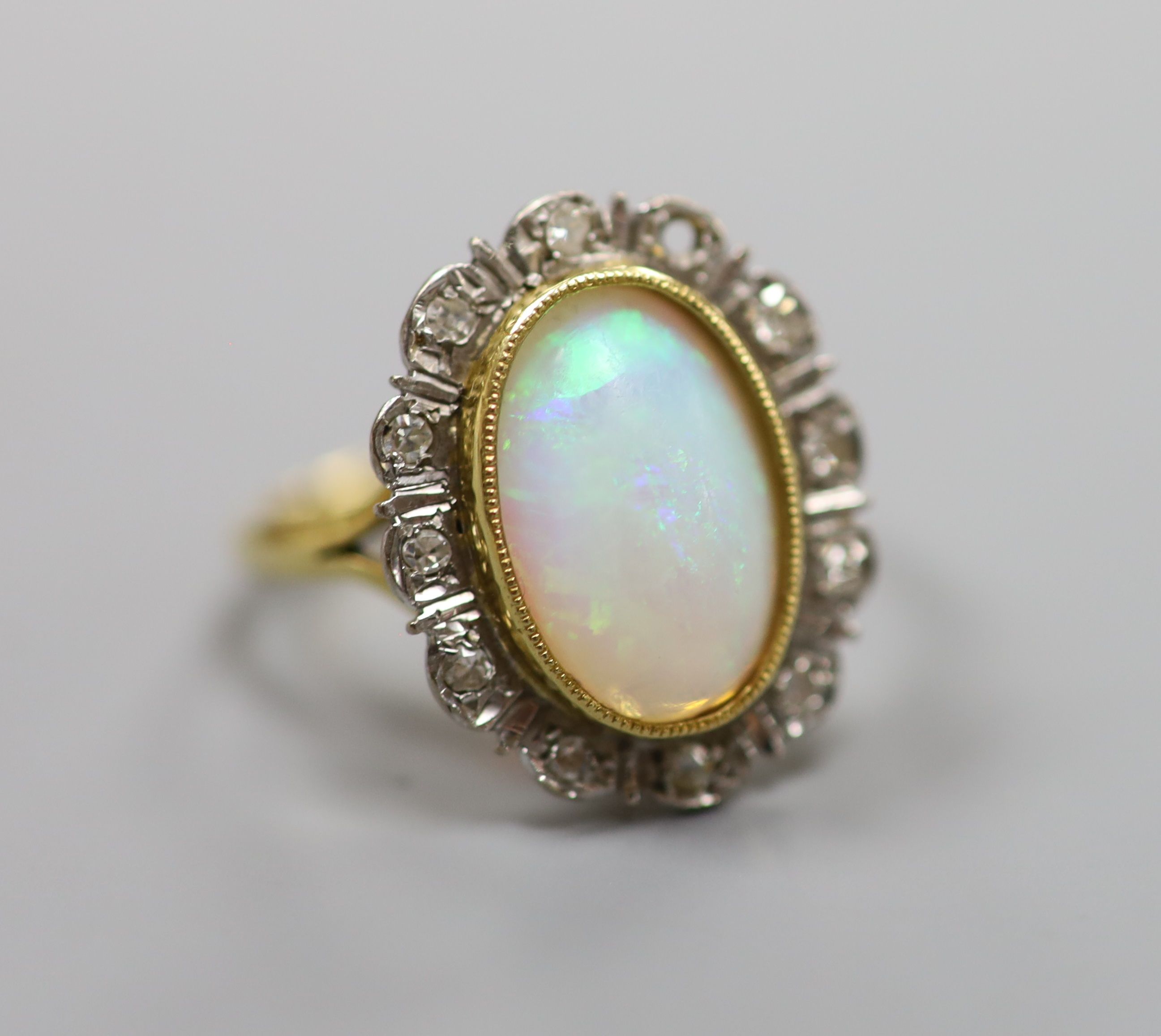 An 18ct, white opal and illusion set diamond oval cluster ring (one diamond missing)